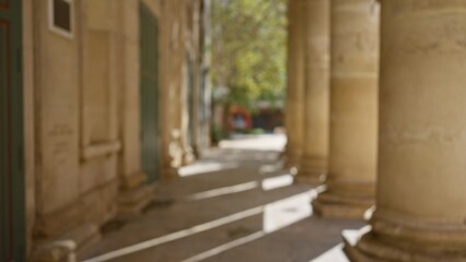 Blurred pillars and defocused outdoor corridor with soft sunlight creating a bokeh effect in the background
