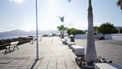 Blurred outdoor scene in lanzarote, canary islands, spain with defocused palm trees and benches under the bright sunny sky