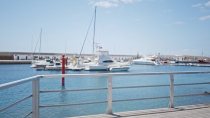 Blurred marina showcasing yachts and defocused background featuring docked boats in bright daylight.