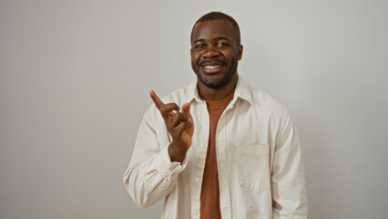Fototapeta premium Young man pointing confidently to the side with a smile on a white background embodying confidence and charm.
