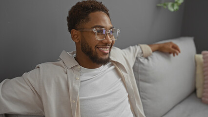 Obraz premium Handsome young man relaxing in a cozy living room at home with a comfortable couch and stylish decor