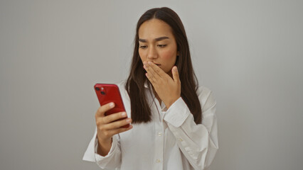 Fototapeta premium Young woman using red smartphone looking surprised in indoor bedroom setting