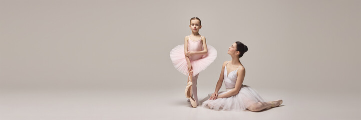 Banner. Little ballerina in tutu stands tall holding ballet slippers while mother kneels nearby, admiring her grace and strength against beige background. Concept of ballet, elegance and beauty, grace