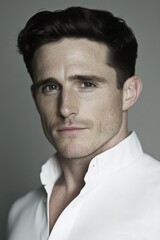 Fototapeta premium Portrait of a young man in a crisp white shirt against a neutral background, exuding confidence and elegance.