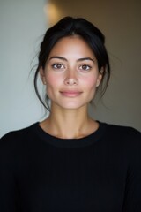 Fototapeta premium A close-up portrait of a young woman with friendly eyes and a gentle smile, set against a neutral background, highlighting her natural beauty.