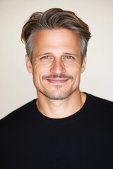 Obraz premium A close-up portrait of a smiling man with blonde hair against a light background. The image has a warm and inviting atmosphere.