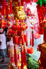 Close-up of Chinese New Year decorations: gold ingots, red lanterns, and firecrackers hang on a string. Festive symbols of wealth, luck, and celebration are ready for the Lunar New Year