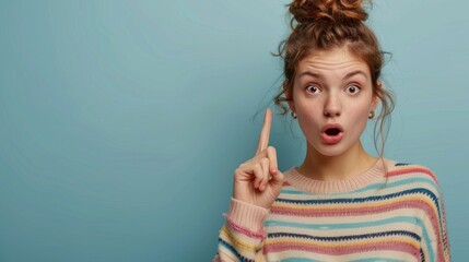 Obraz premium Girl in bright sweater with surprised expression and raised finger. Ideal for articles about psychology, education and personal growth.