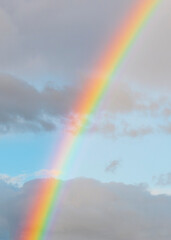 amazing bright rainbow in beautiful evening blue cloudy sky with falling rain drops and sun light streaming thruogh the clouds, weather thunderstorm concept