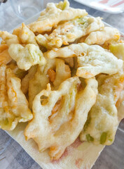 Fried zucchini flowers resting on white paper napkin