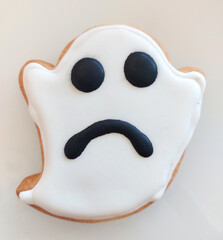 Sad ghost cookie decorated with icing for Halloween party