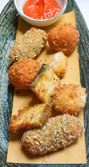 Fried zucchini, suppli and fried mozzarella with tomato sauce being served as appetizer