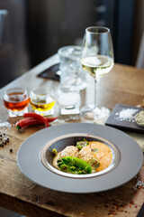 Scallops with shrimp foam, cauliflower cream and green peas on a plate. Delicious healthy seafood closeup served for lunch on a table in modern gourmet cuisine restaurant