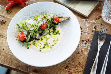 Vegan warm asparagus-broccoli salad with dill aioli, vegan cheese. Delicious healthy vegeterian food served for lunch on a table in modern gourmet cuisine restaurant