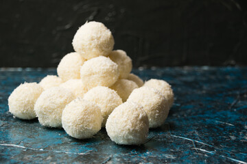 Delicious homemade candies with coconut flakes and almonds on a dark background. Concept of delicious holiday homemade dishes