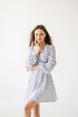 beautiful woman model posing in white polka dot dress in studio
