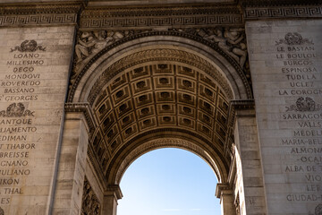 Visitors admire the impressive architecture of the Arc de Triomphe under clear blue skies in Paris 