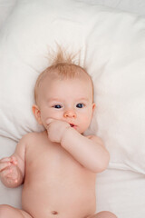 small beautiful child with blue eyes, holding hands in mouth
