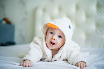 portrait of  toddler lying on bed in duck robe