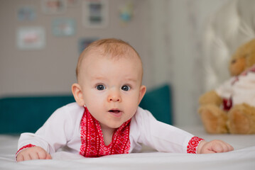 newborn baby boy lying on bed in Ukrainian embroidery at home surprised thoughtful
