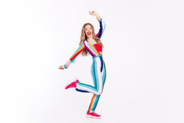 Joyful young woman in colorful striped outfit dancing gracefully against a white background