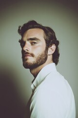 Obraz premium Portrait of a young man in a white shirt with a thoughtful expression. The muted colors give a vintage and sophisticated vibe.
