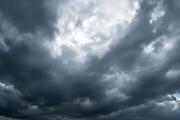 Fototapeta premium Dark stormy clouds with dim light breaking through, creating a dramatic sky concept.
