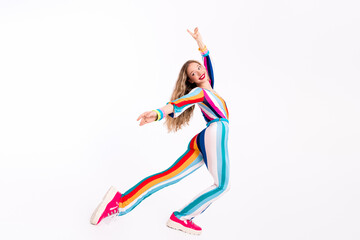 Energetic young woman dancing joyfully in a colorful, trendy striped jumpsuit against a clean white background