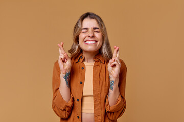 A Joyful and Cheerful Young Woman with Her Fingers Crossed in a Trendy and Stylish Outfit