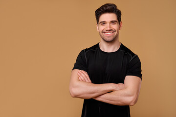 A Smiling Man Wearing a Black TShirt Poses Confidently Against a Beige Background