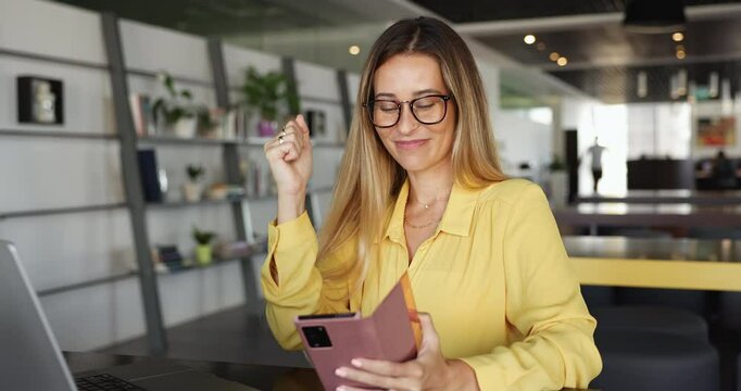 Woman office employee sit at workplace read fantastic news on smartphone, celebrate, make yes gesture, receive salary notice, positive feedback from client, being rewarded, personal growth achievement