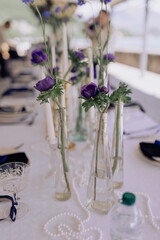Elegant wedding table setting with purple floral arrangements, gold candleholders, and white tablecloth overlooking the lake