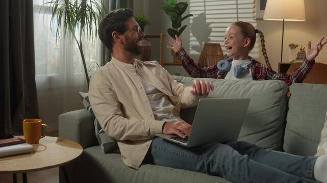 Caucasian man male freelancer user businessman at home couch father working business laptop using computer little girl daughter child kid suddenly jumping surprise scare dad playing laughing family