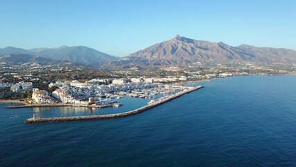 aerial view of luxury yachts in Puerto Banús marina, habor wall and the lighthouse Faro Puerto...