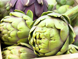 Obraz premium Close-up of fresh green artichokes with purple highlights in a box