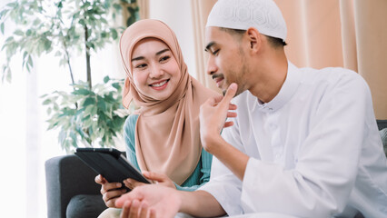 Happy Muslim family moment as a couple connects through digital learning, strengthening their religious bond, cultural heritage, and spiritual devotion in a serene home setting.