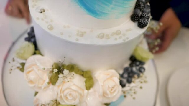 Multi-tiered wedding cake made of mastic decorated with cream roses