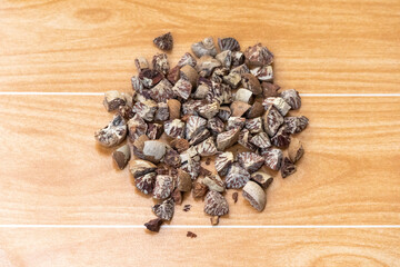 Betel nut fruit, scientifically known as Areca catechu and locally known as Supari in Bangladesh, is cut into small pieces and displayed on a wooden background.