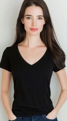 A confident woman with long brown hair wears a simple black t-shirt and jeans, standing against a neutral background. Her expression is serene and poised.