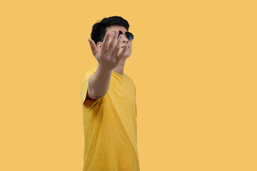 Confident young asian Man Gesturing Dramatically in Sunglasses Against Solid Yellow Background