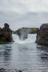 Hjalparfoss waterfall in South Iceland, framed by rugged basalt rocks.