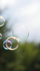 A close-up shot of colorful soap bubbles being blown against a blurred outdoor background, close-up, outdoor