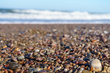Close-up of Colorful Pebbles on a Beach with Waves in the Background