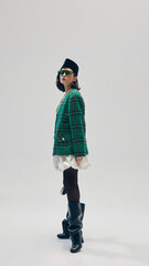 Full-length. Stylish young woman with dark short hair, in green plaid blazer, white skirt, beret,...