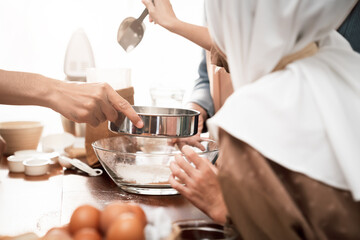 Happy Muslim family preparing a homemade dessert, parents teaching kids the art of baking, sharing smiles, love, and togetherness in a cozy and festive home environment