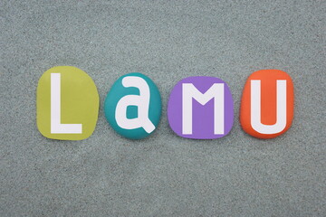 Lamu, small town on Lamu Island, which in turn is a part of the Lamu Archipelago in Kenya, souvenir composed with multi colored hand painted stone letters over green sand