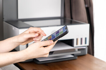 Operating a Wireless Printer via Smartphone App, Hands Interacting with the Screen While the...