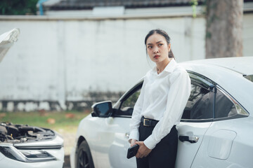 Car Trouble: A young woman stands beside a broken down car with a look of concern on her face. The...