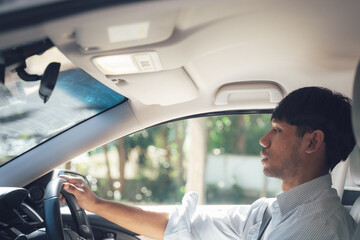 Fototapeta premium Driving Commute: A man in a crisp white shirt drives his car, focused on the road ahead. The image offers a glimpse into the daily routine of a modern professional.