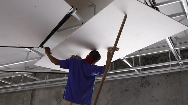 Builders do repaire in office. In the office make repaire during hot and suny day in Asia. The man works at construction in showroom